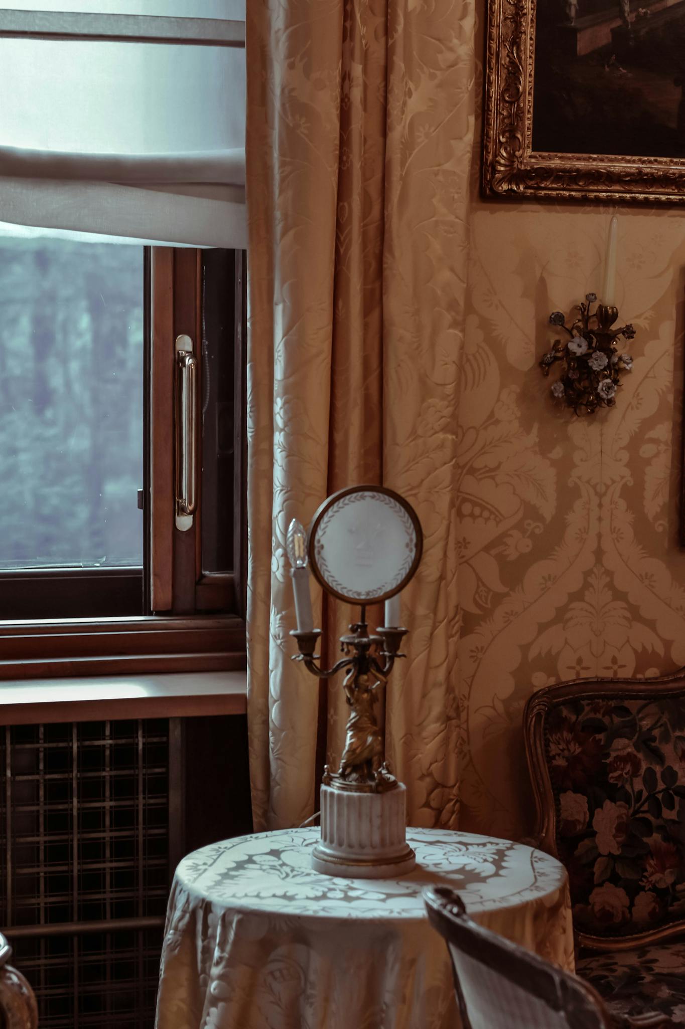 A serene vintage room featuring a decorative lamp on a table by a window.