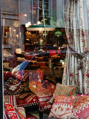 A vibrant display of colorful patterned cushions in a cozy shop window setting.