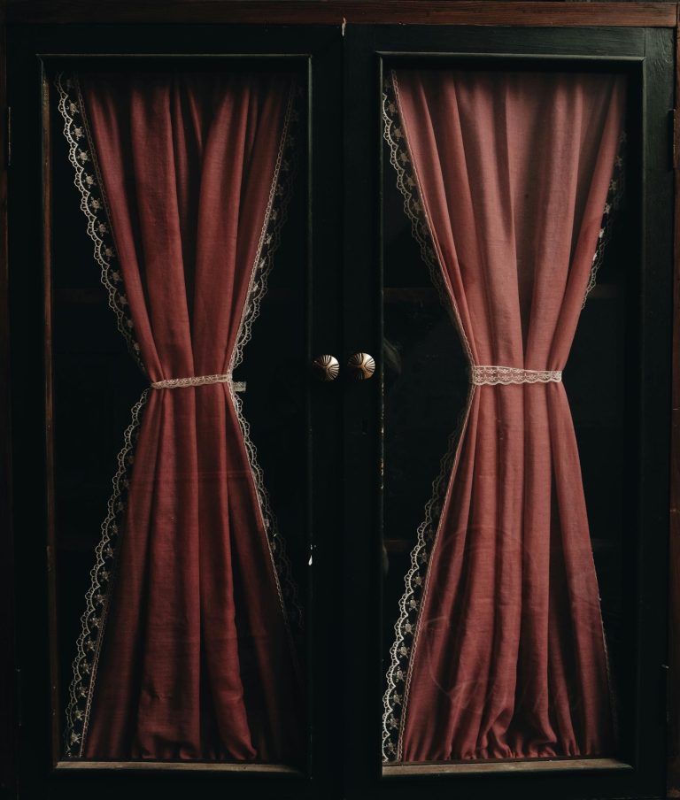 Dark vintage red curtains with lace trim create a luxurious and dramatic aesthetic.