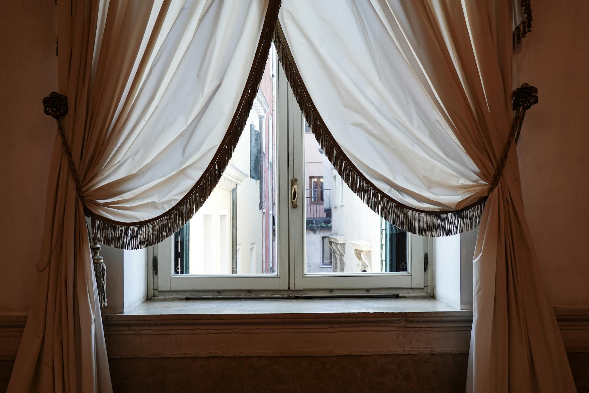 Luxurious draped curtains framing a vintage window in an ornate interior setting.