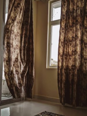 Warmly lit indoor setting featuring elegant draped curtains and a decorative rug.